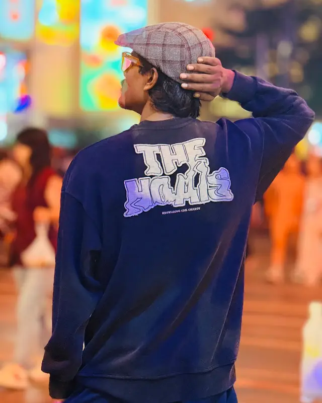 Rapar Rubel seen from behind in a sweatshirt that reads The Homies, knowledge can change