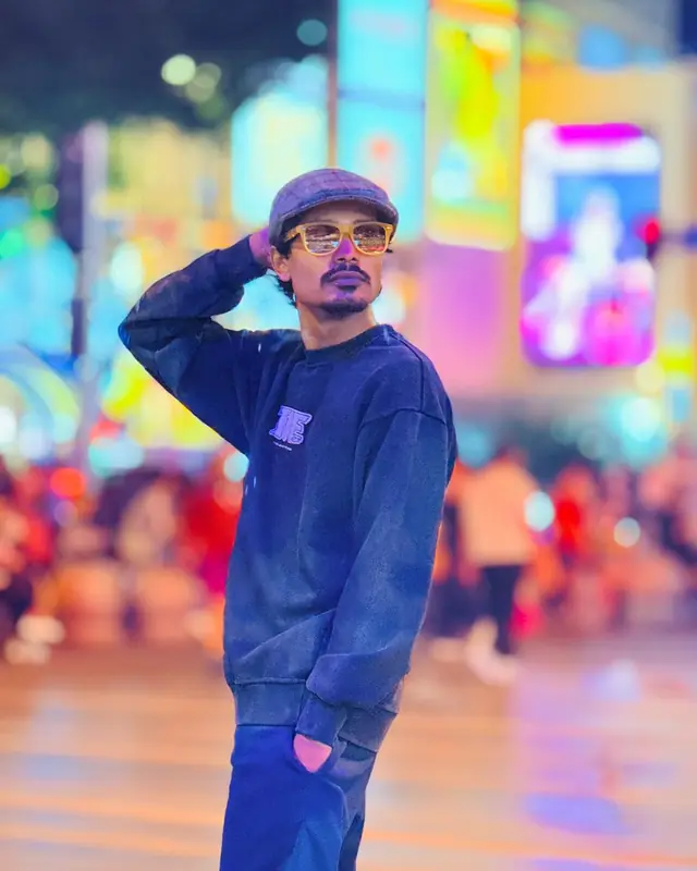 Rapar Rubel posing under neon city lights