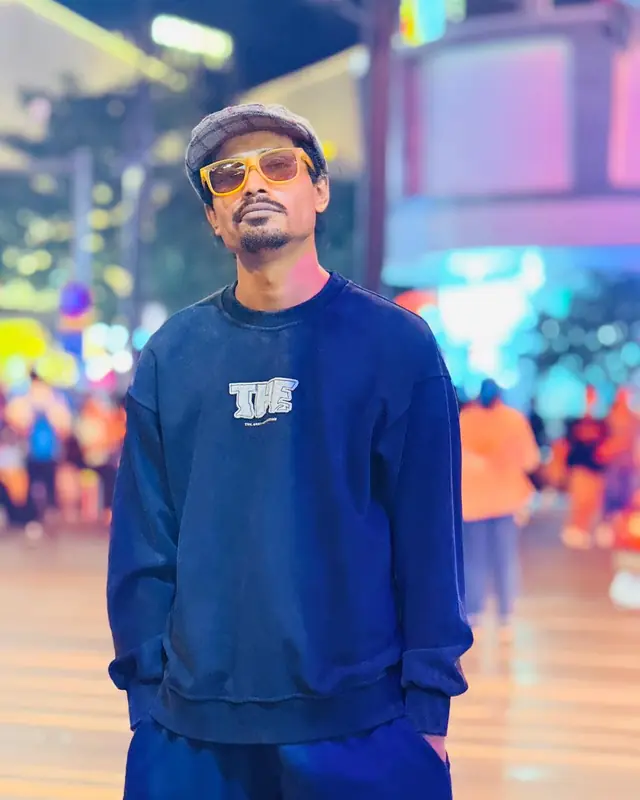 Rapar Rubel at night in a city street wearing a cap and sunglasses