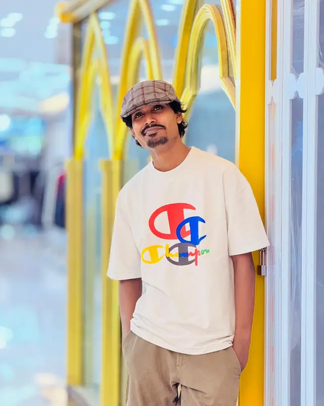 Rapar Rubel smiling in a white T-shirt and flat cap