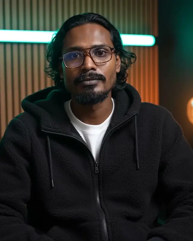 Rapar Rubel in a studio wearing glasses and a black fleece